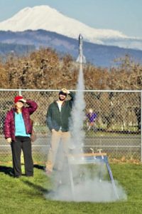People watching a rocket liftoff in front of Mount Adams