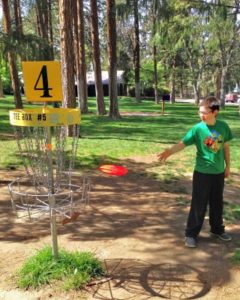 Kid playing disc golf at Sorosis Park 